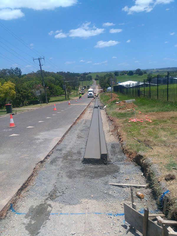 A concrete curb is being built on the side of a road.