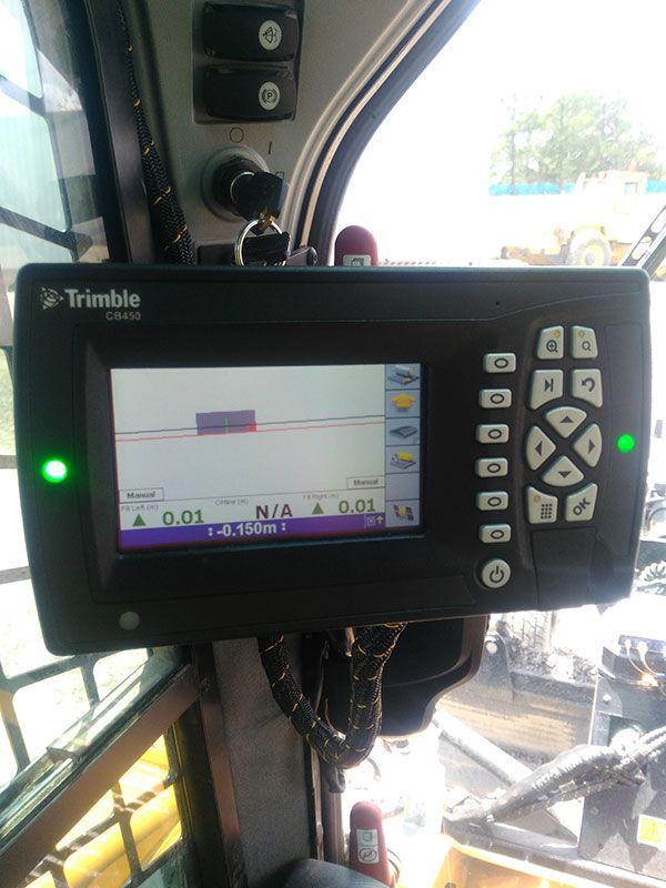 A trimble monitor is sitting in the cockpit of a bulldozer.