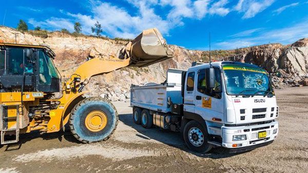 A dump truck is parked next to a bulldozer in a quarry.