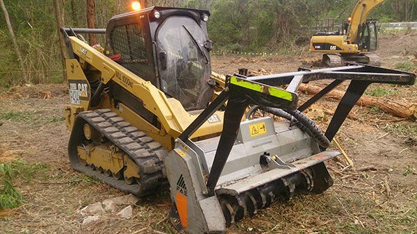 A bulldozer is sitting in the middle of a forest.