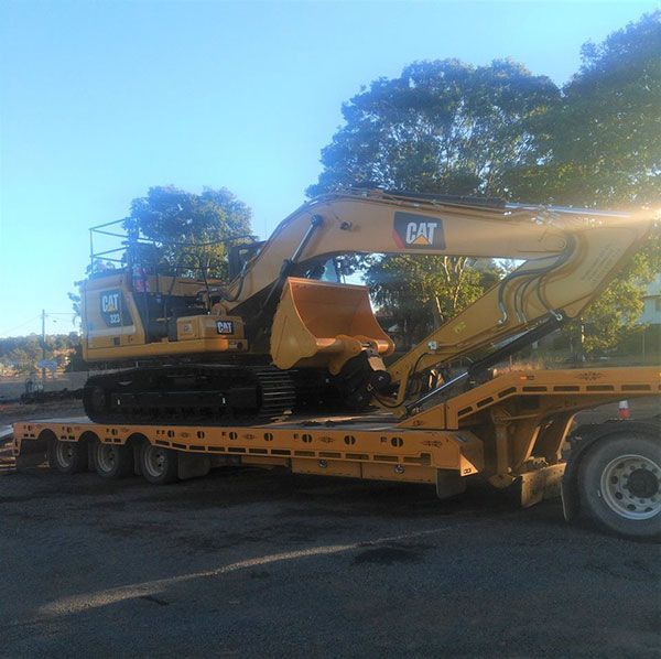 A yellow cat excavator is on a flatbed trailer