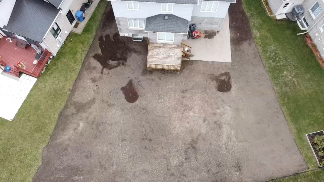 Une vue aérienne d’une cour avec une maison en arrière-plan.