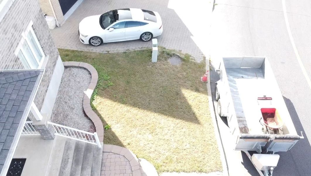 Une voiture blanche est garée dans l’allée d’une maison.