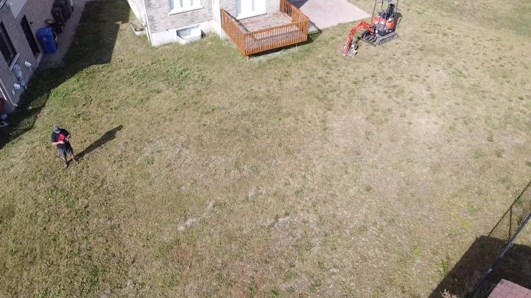 Une vue aérienne d’une pelouse avec une maison en arrière-plan.