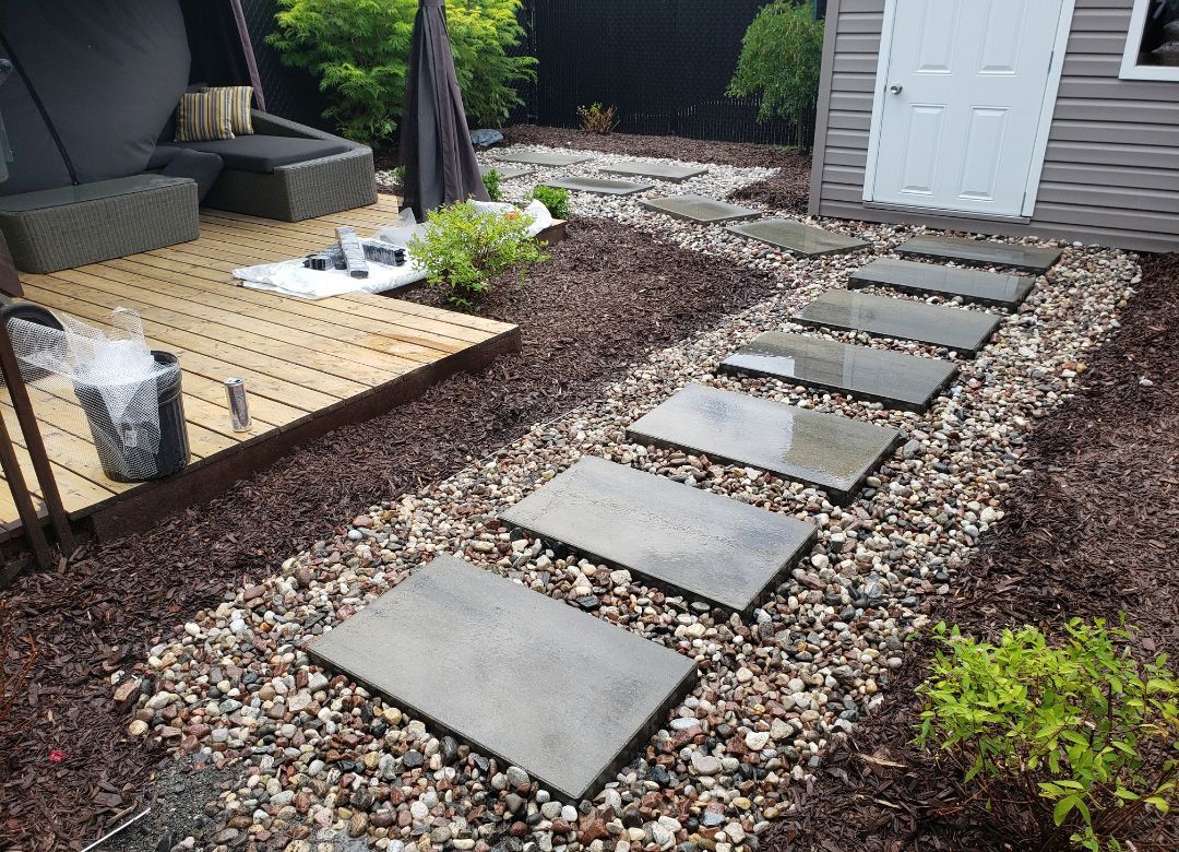 Une passerelle en pierre menant à un cabanon dans une cour arrière.