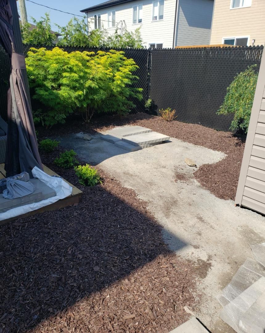 Une cour avec une passerelle en béton et une clôture noire.