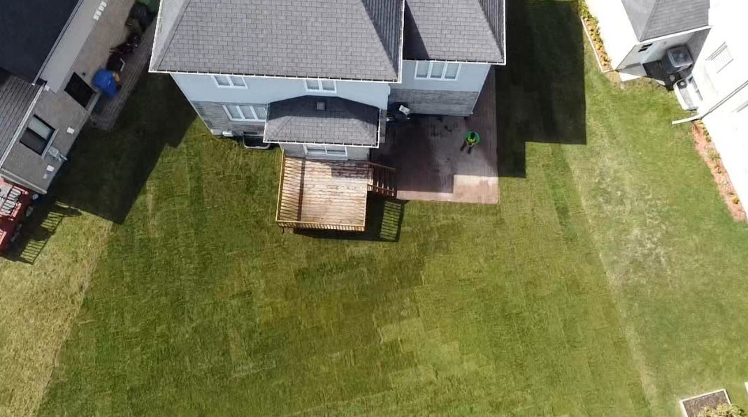 Une vue aérienne d’une maison avec une grande pelouse devant elle.