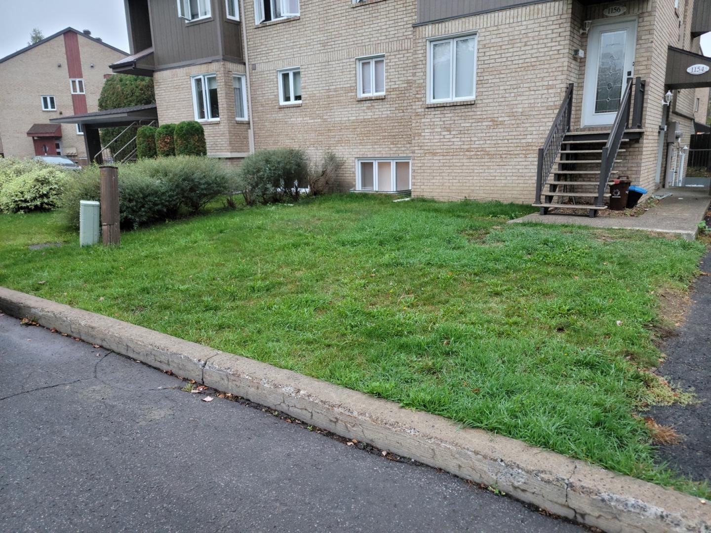 Une maison en brique avec une pelouse verte luxuriante devant elle.