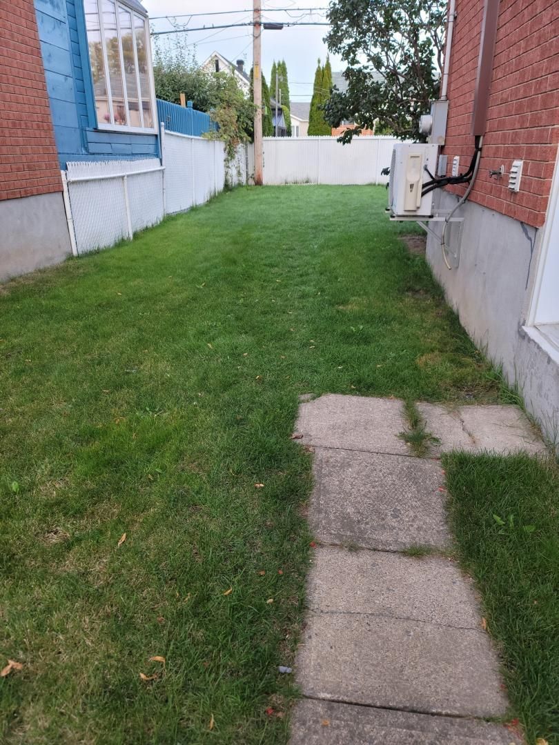 Une maison en brique avec une pelouse verdoyante et un trottoir qui y mène.