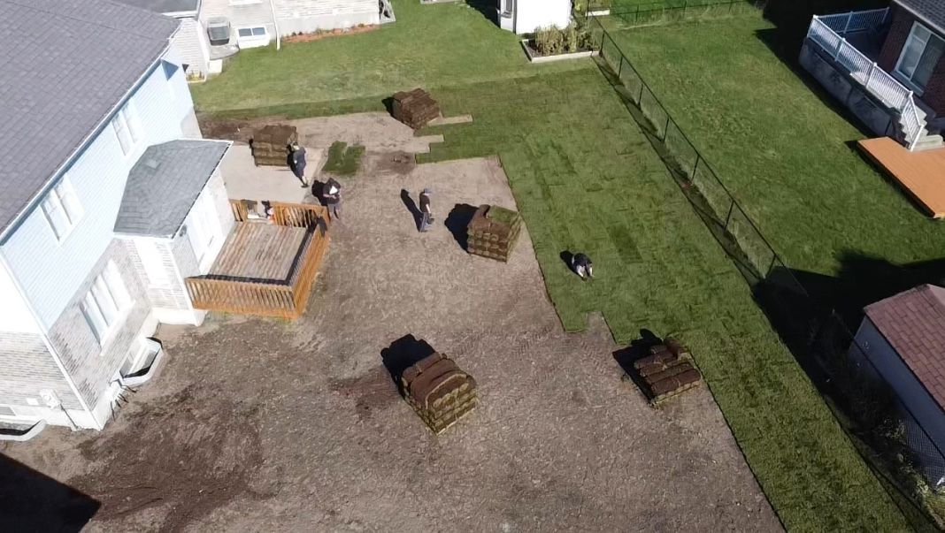 Une vue aérienne d’une cour avec beaucoup d’herbe et une maison en arrière-plan.