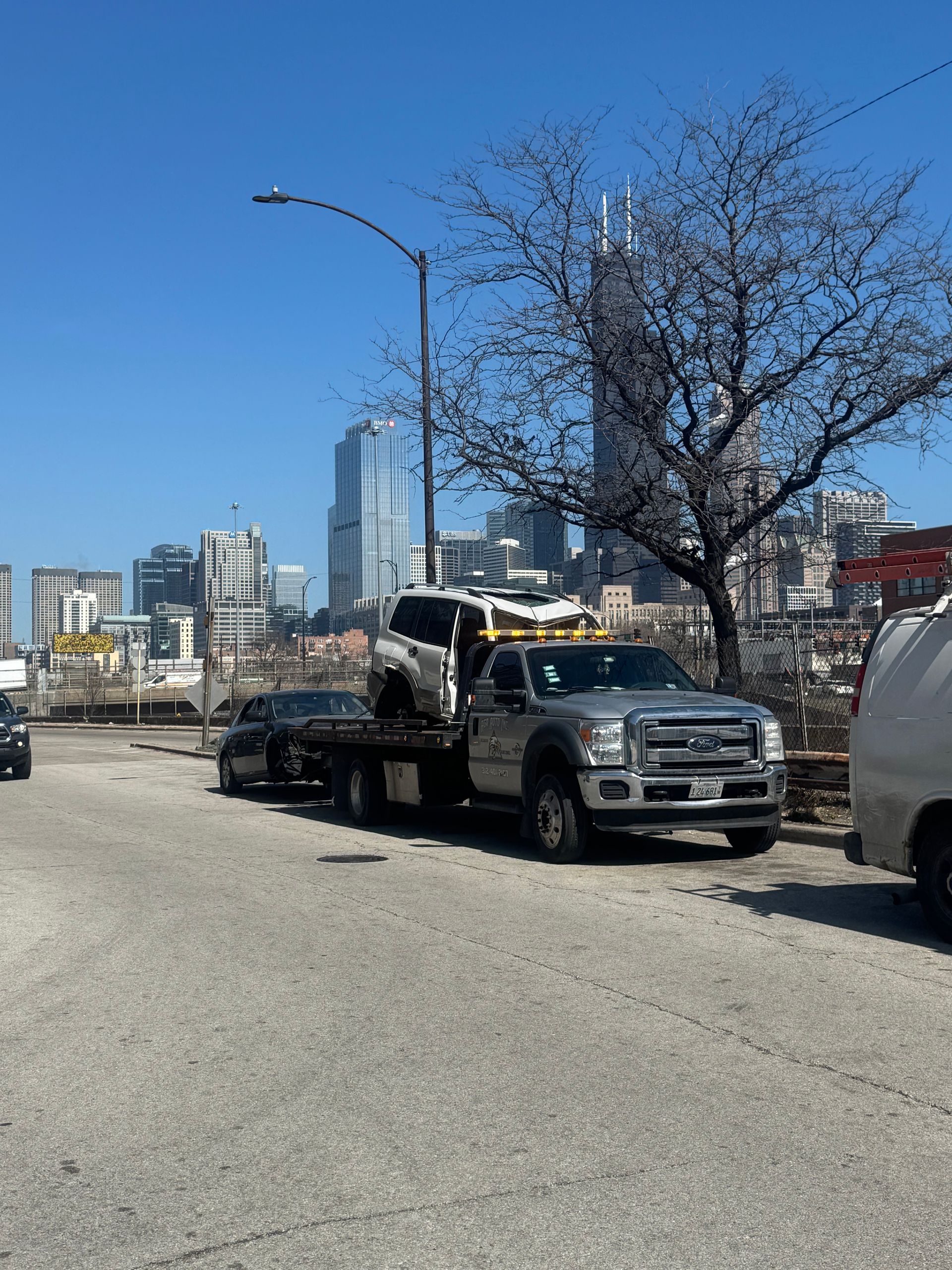 A woman is using a cell phone in front of a broken down car.