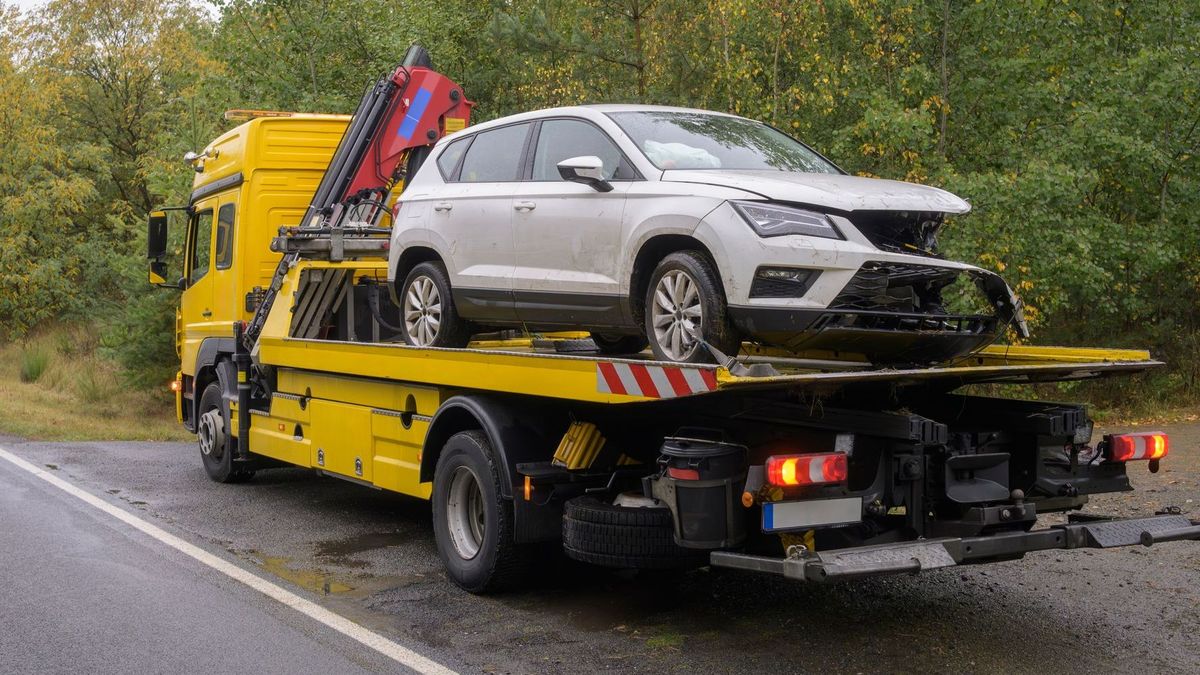 A tow truck is towing a car on the side of the road.