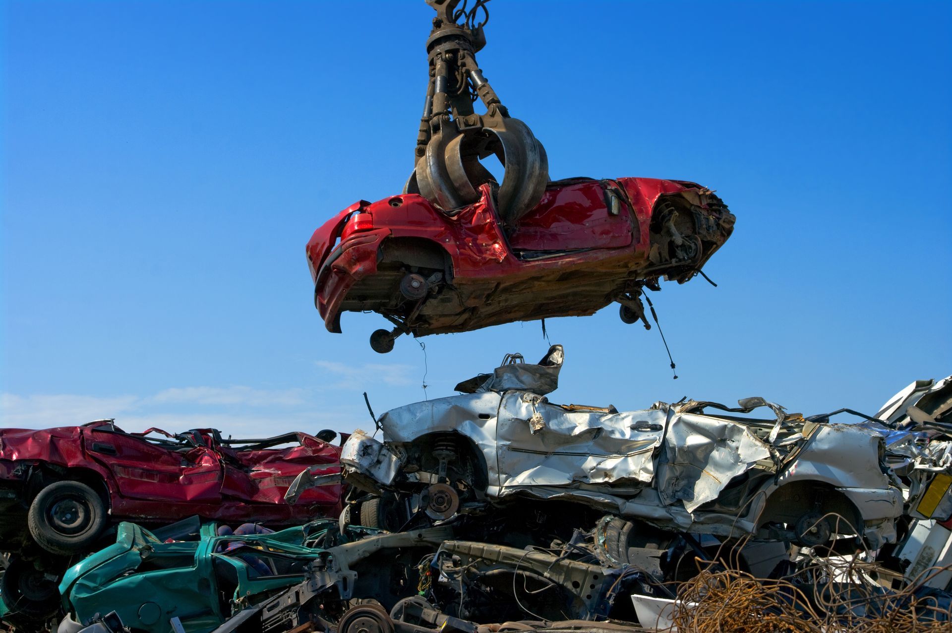 A red car is being lifted into the air by a crane.