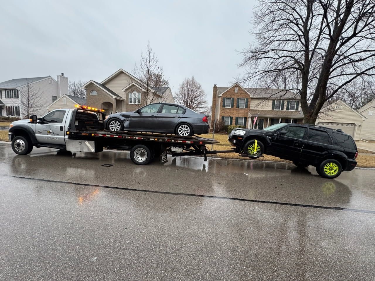 A tow truck is towing a damaged car on a highway.