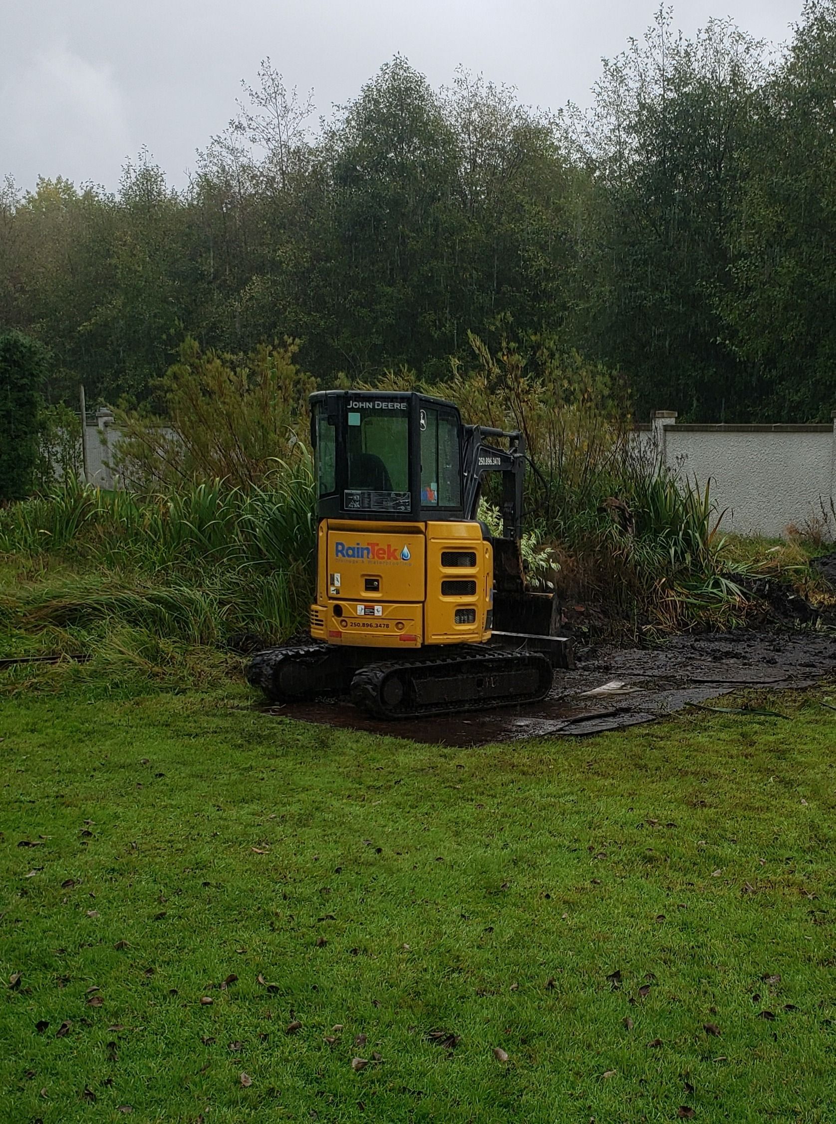 A bobcat with the RainTek logo on it digging a trench