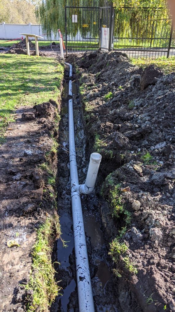 a drain pipe laid in a trench as part of a drainage system designed to draw water away from yard to prevent lawn pooling
