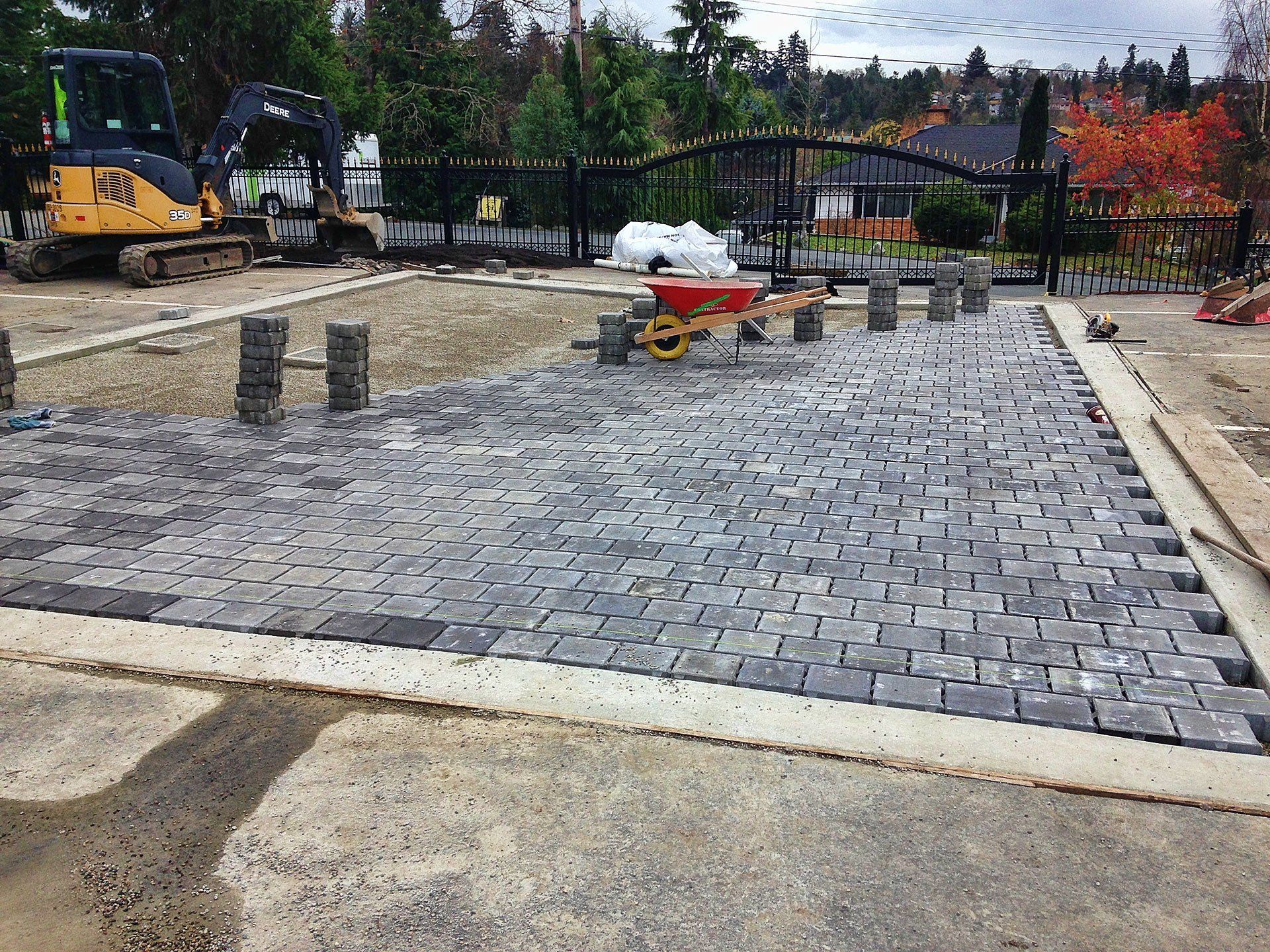 Image of landscape service experts in Victoria BC installing a permeable surface of stone pavers over a rainwater harvesting system