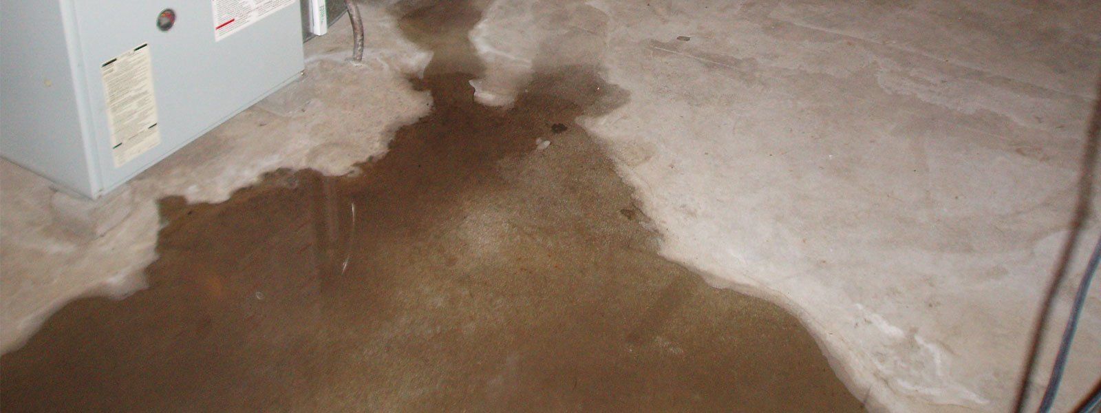 Water leaking into a basement and spreading across the concrete floor