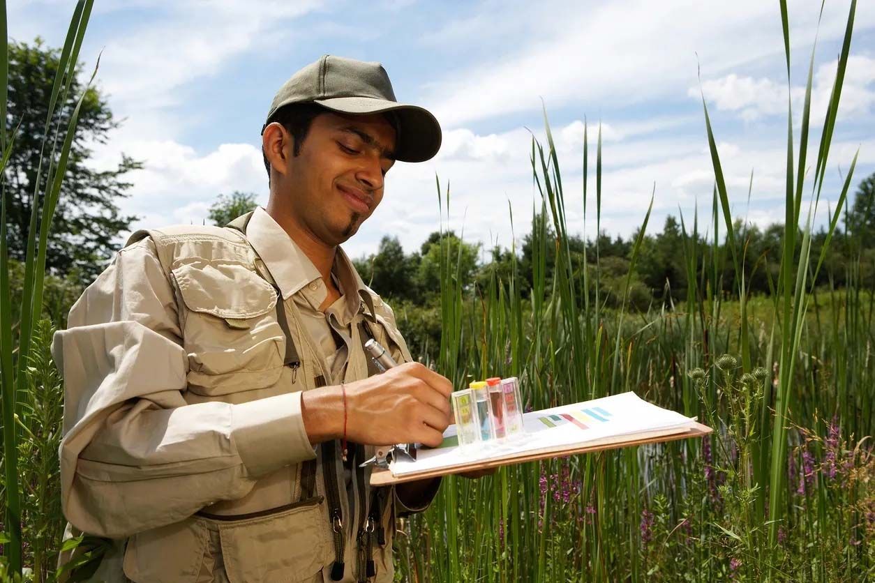 a man is writing on a clipboard in a field
