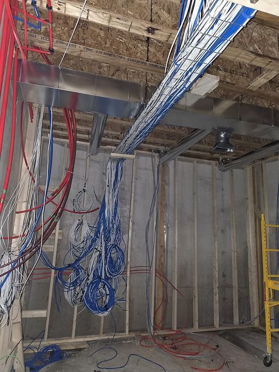Electrical and plumbing infrastructure under construction, with hanging blue and red wires.