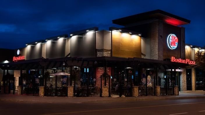 Boston Pizza restaurant at night, with outdoor patio seating and illuminated signage.