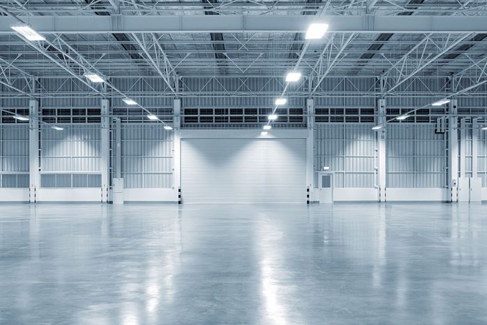 Large empty warehouse with a polished concrete floor and a closed loading door.