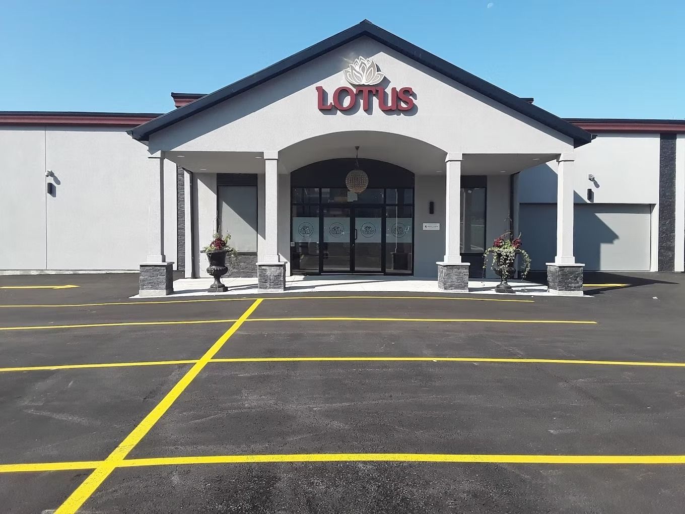 Lotus restaurant exterior with a grey facade, arched entrance, and parking lot.