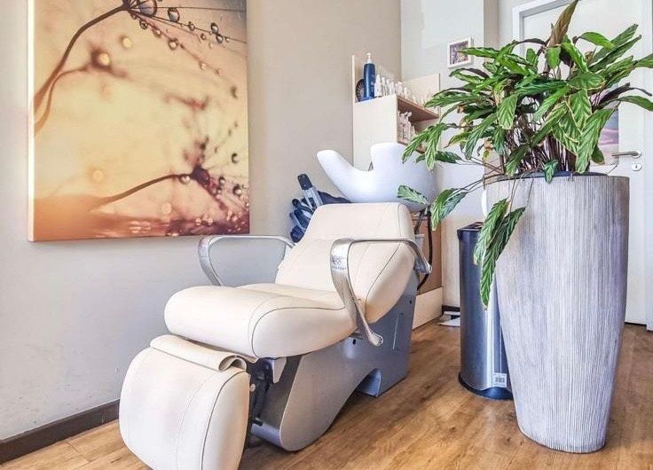 Ein Friseursalon mit Stuhl, Waschbecken und Topfpflanzen.