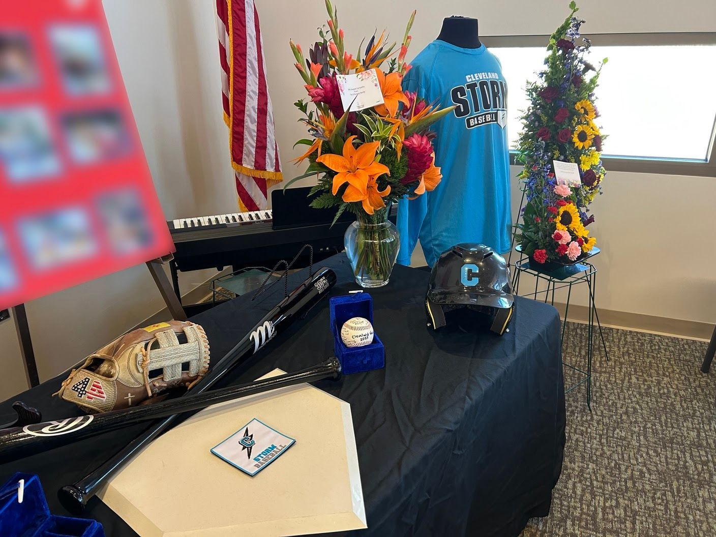 Bright floral bouquets and photo display around the baseball-themed memorial table, adding warmth and cherished memories.