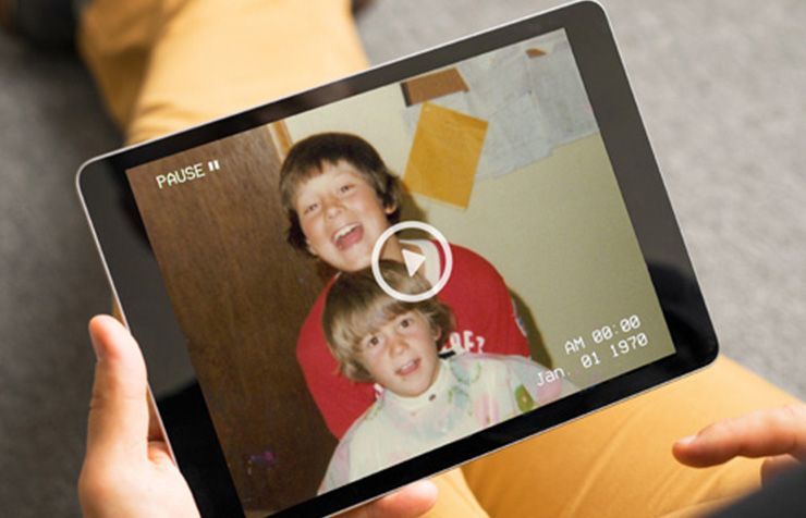 A person is holding a tablet with a picture of two children on it