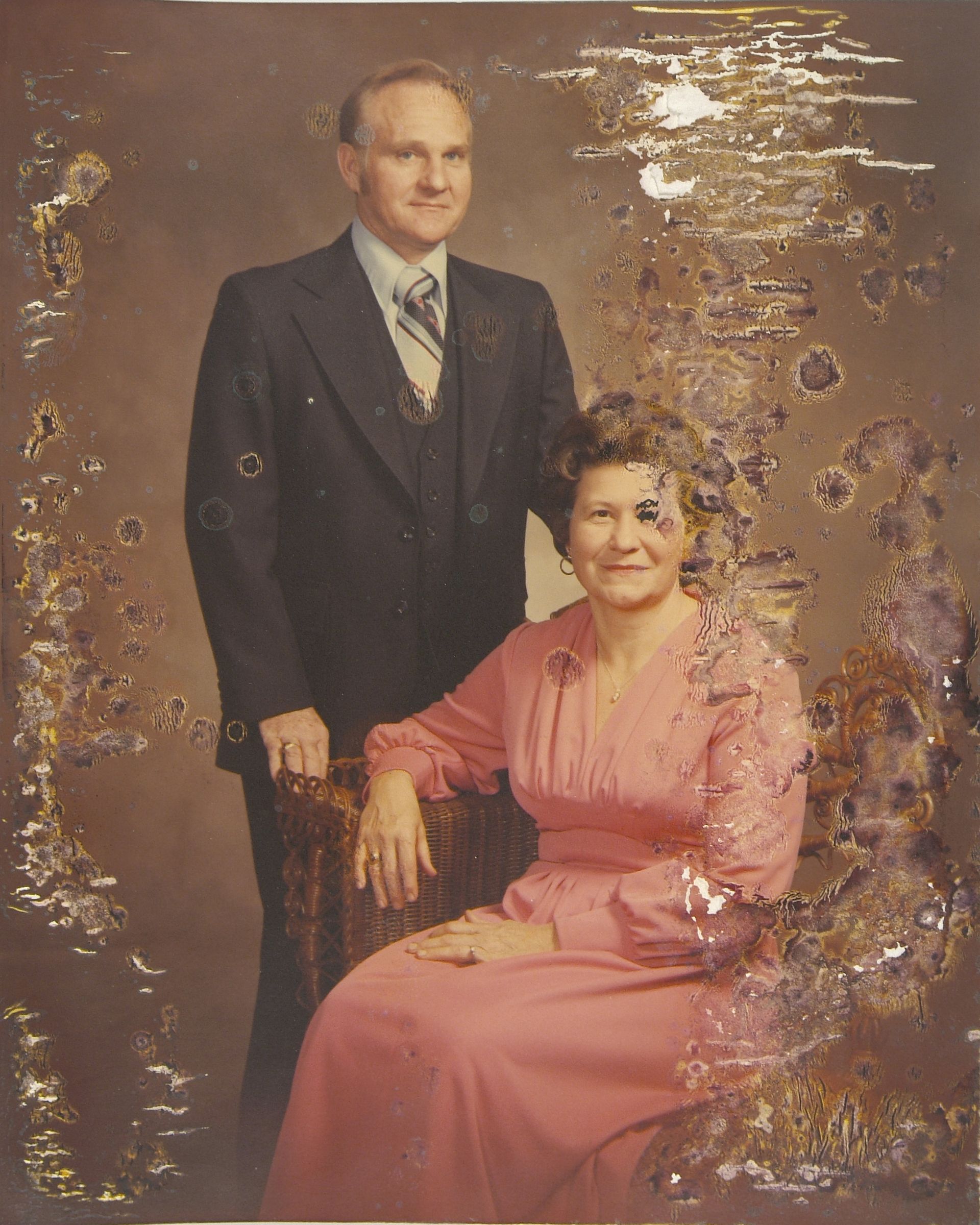 A man in a suit and tie stands next to a woman in a pink dress