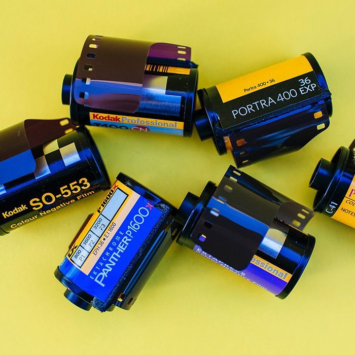 Several rolls of kodak film are laying on a yellow surface