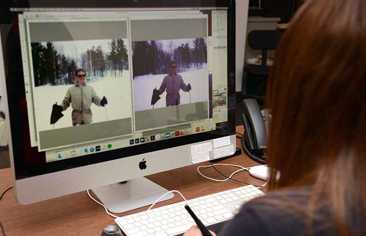 A woman is sitting at a desk in front of an apple computer.