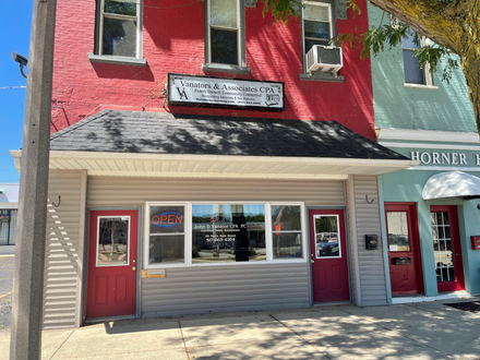 Exterior view of a red brick building with a business sign above the entrance and a tan storefront.