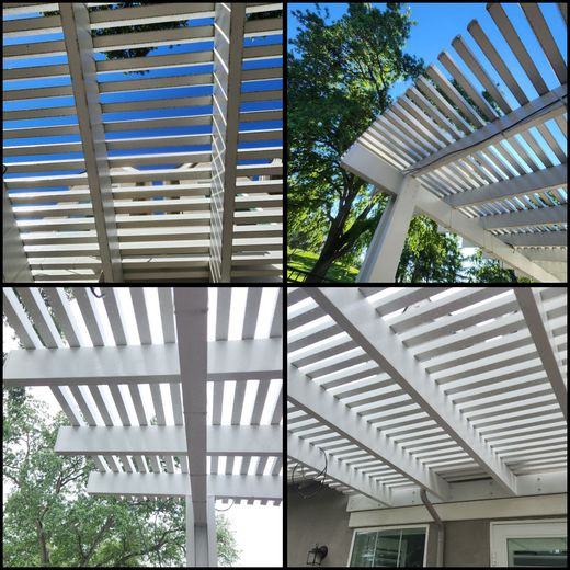 White pergola slats and beams seen from below, casting striped shadows against blue sky and trees.