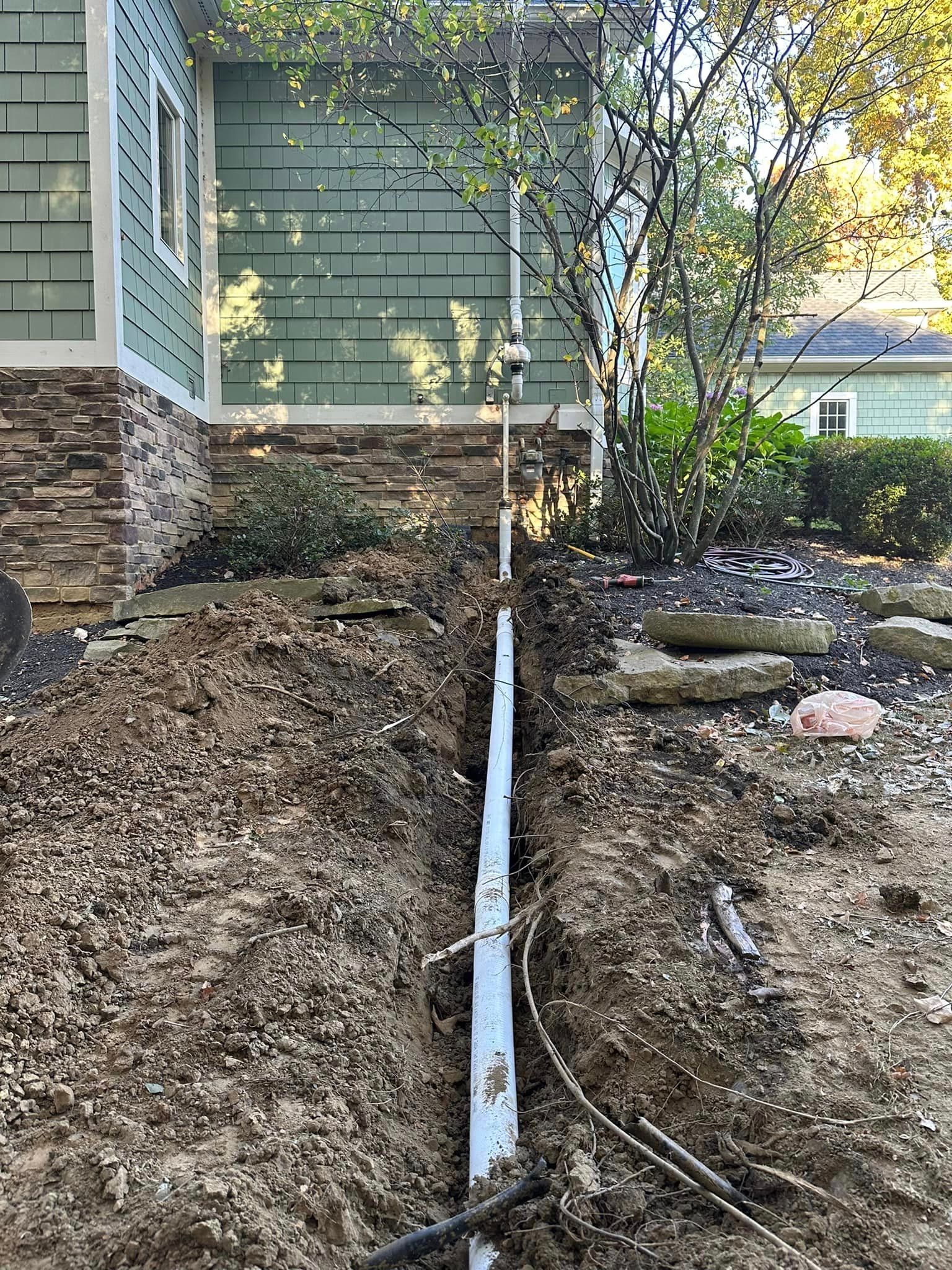 a pipe is being installed in the dirt in front of a house .