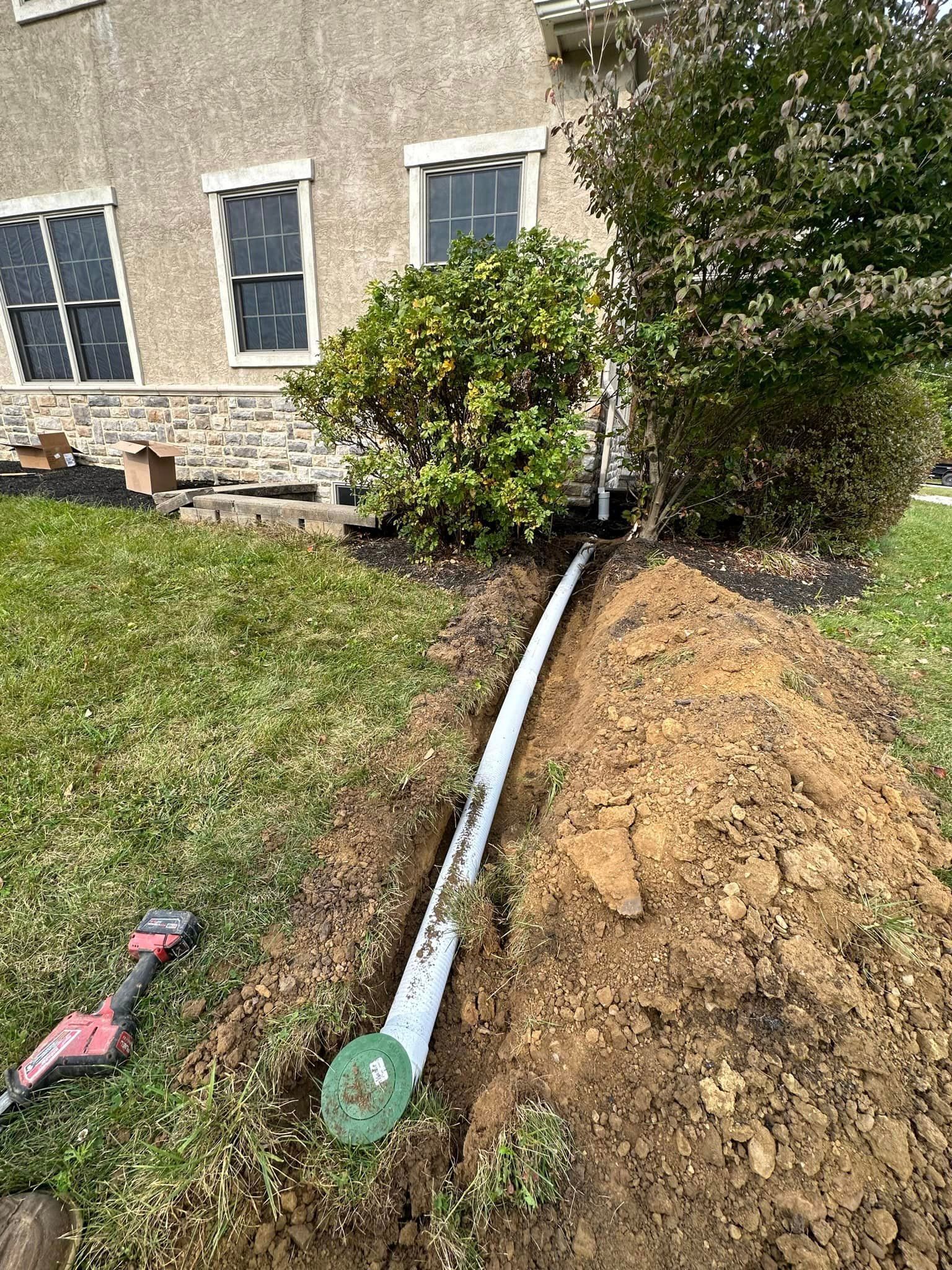 a pipe is being installed in the dirt in front of a house .