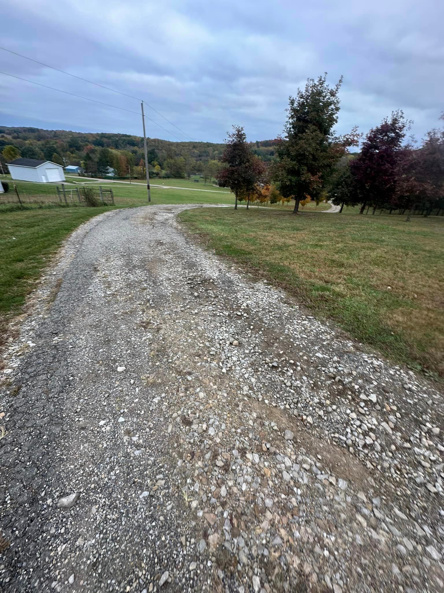 a gravel road going through a grassy field .