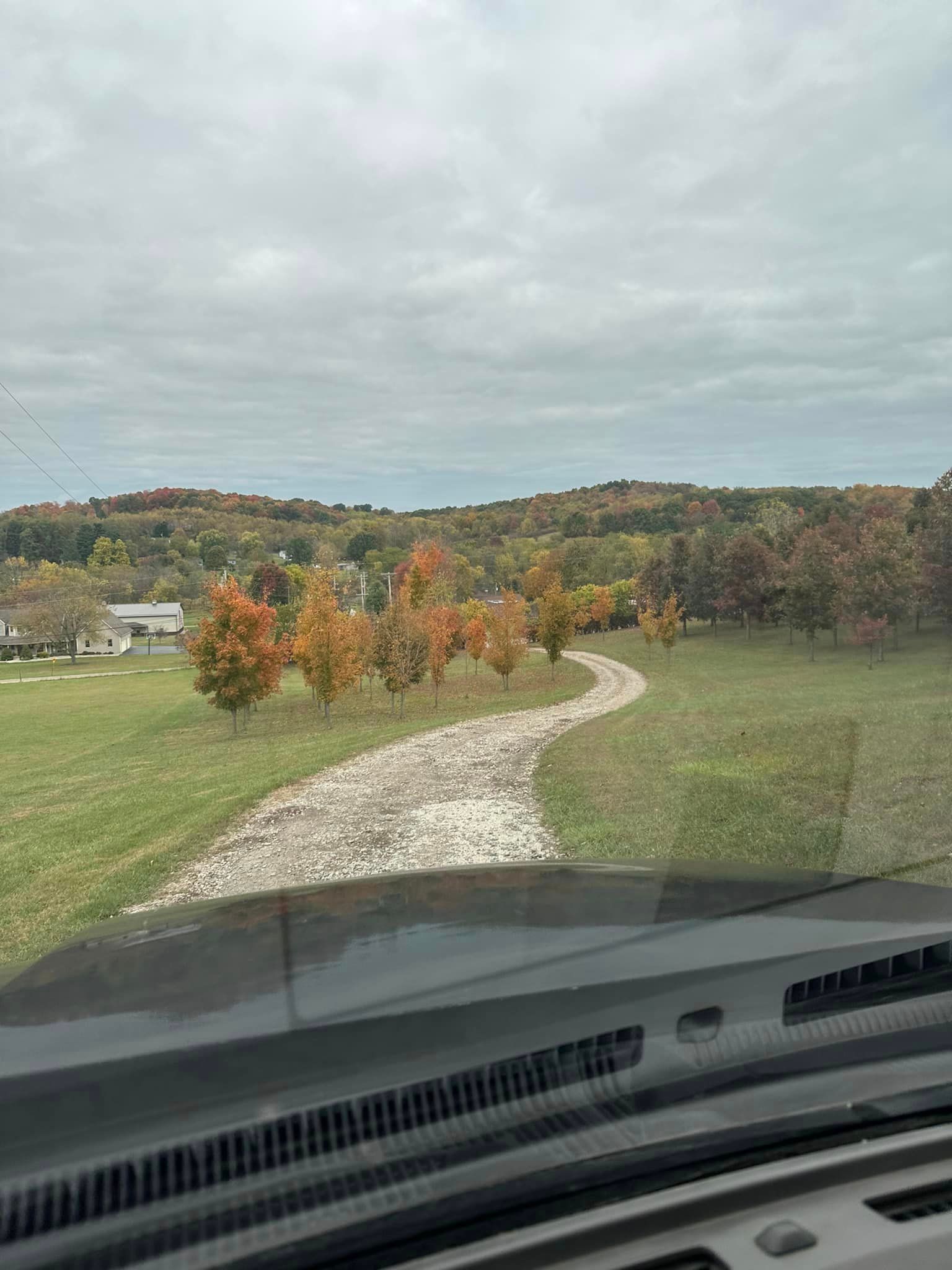 A car is driving down a dirt road in a field.