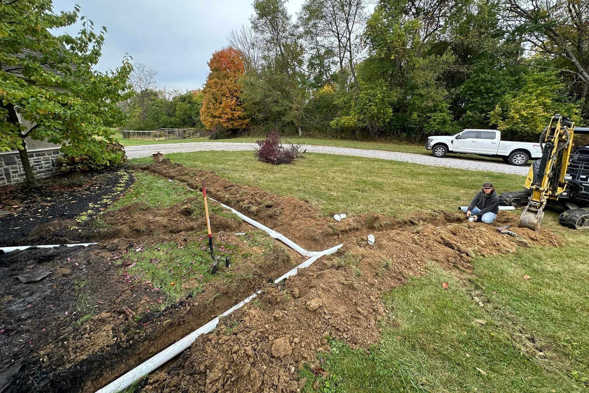 a man is sitting on the ground next to a pipe in a yard .