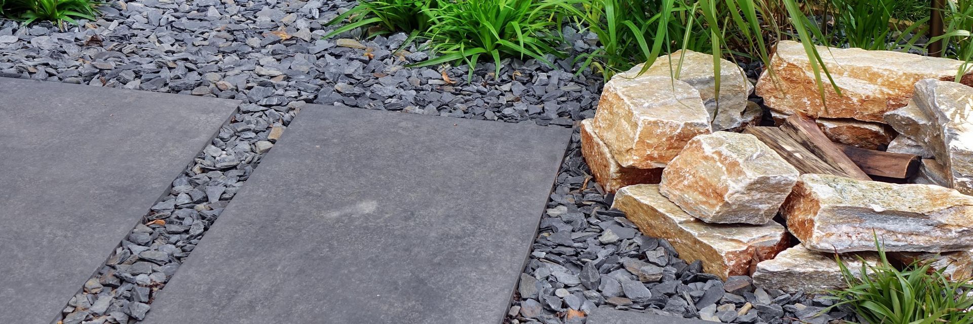 a stone walkway surrounded by rocks and gravel in a garden .