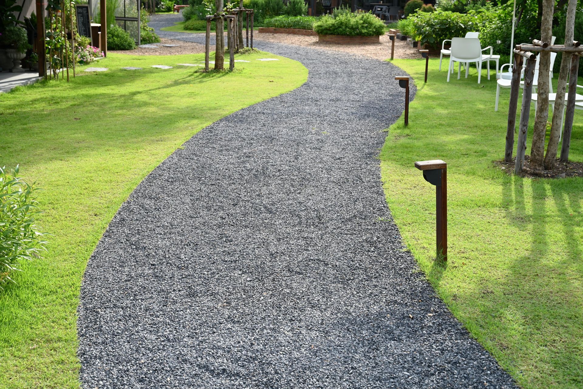 a gravel path winds through a lush green garden .