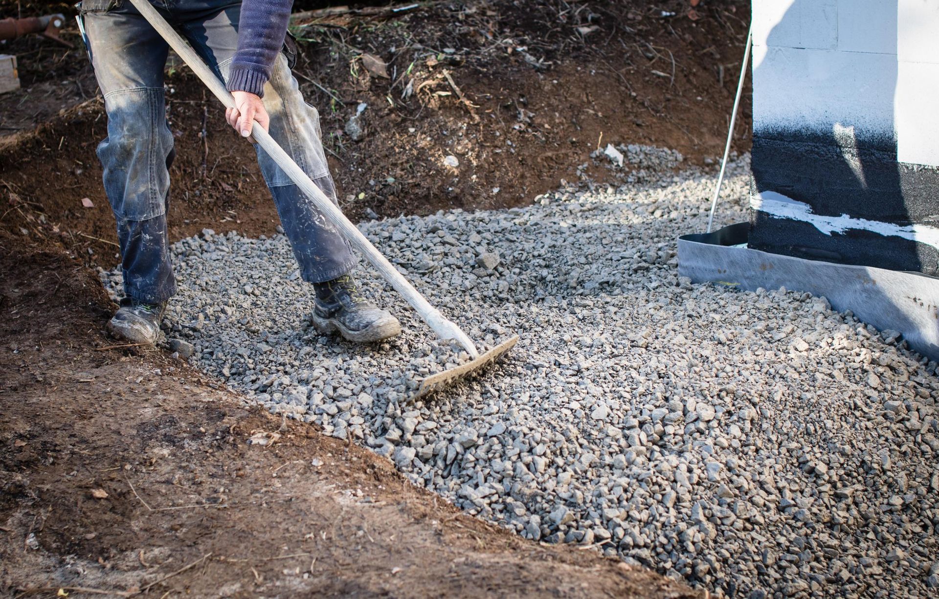 a man is raking gravel with a broom .