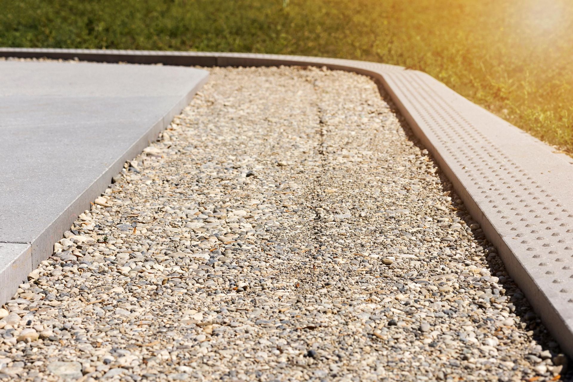 a gravel road with a drain on the side of it