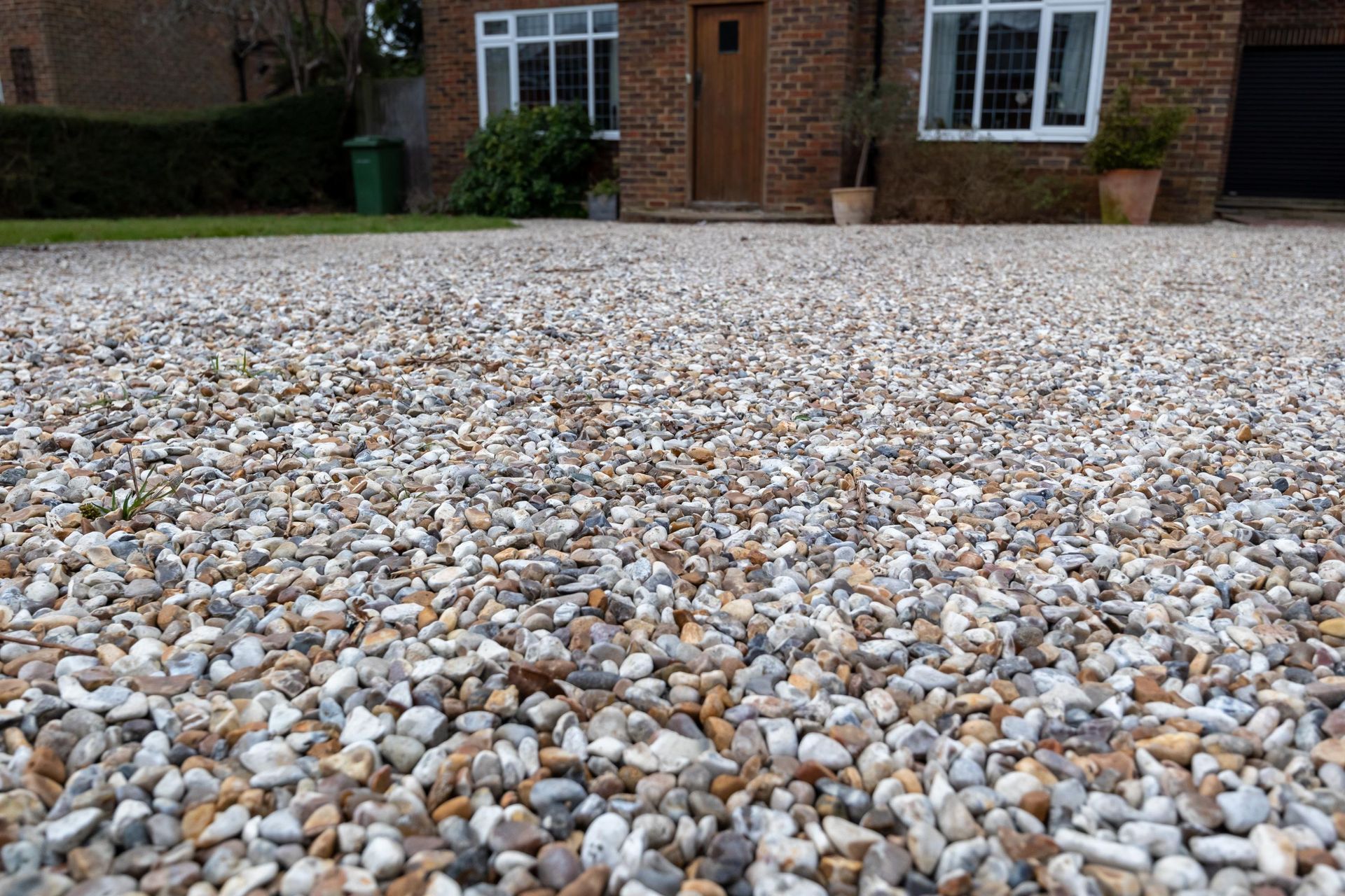a gravel driveway in front of a brick house .