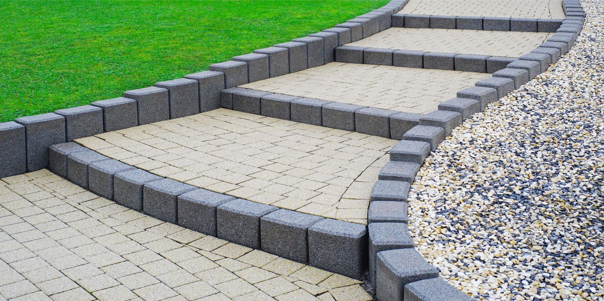 a brick walkway leading to a lush green lawn .