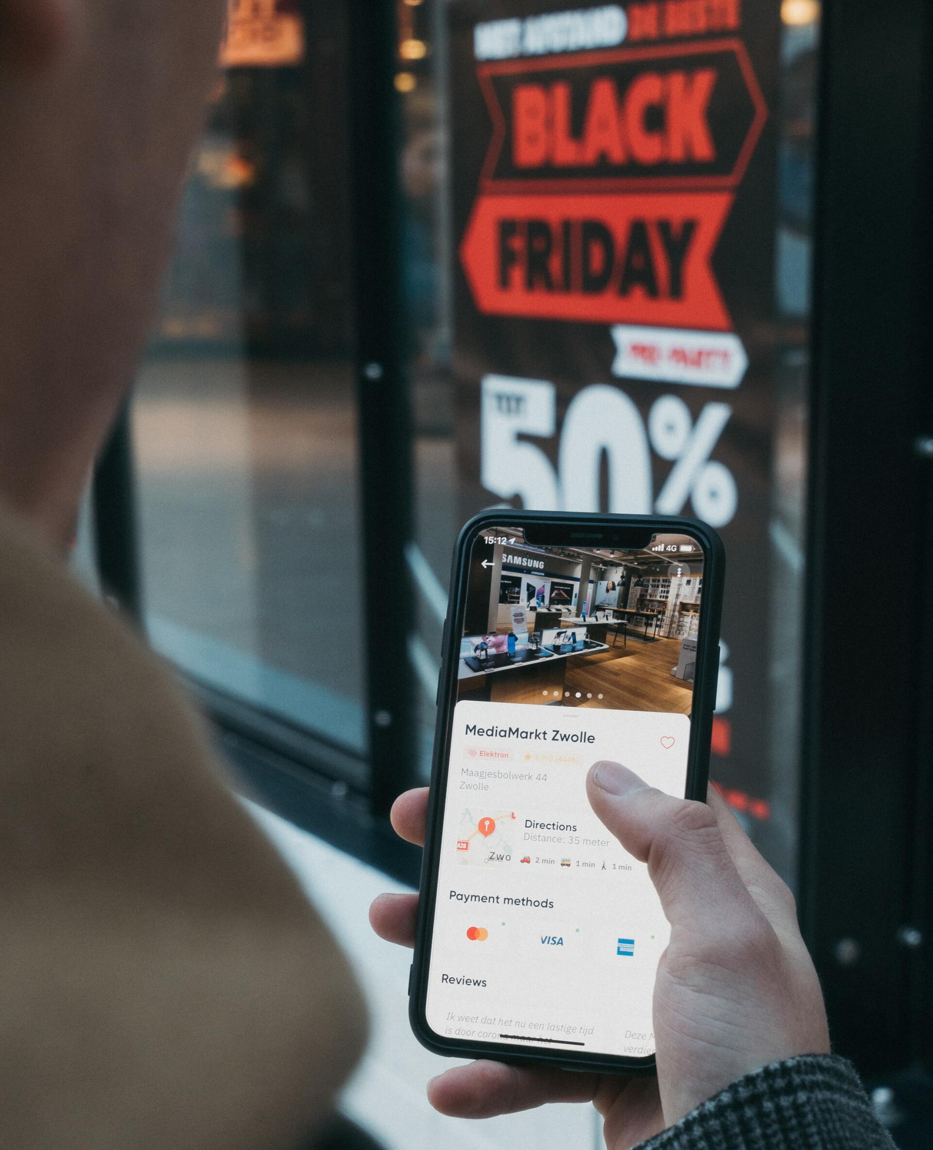A person is holding a cell phone in front of a black friday sign