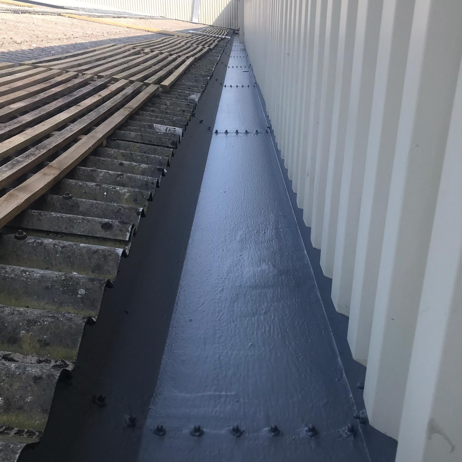 A drain on the side of a building next to a roof