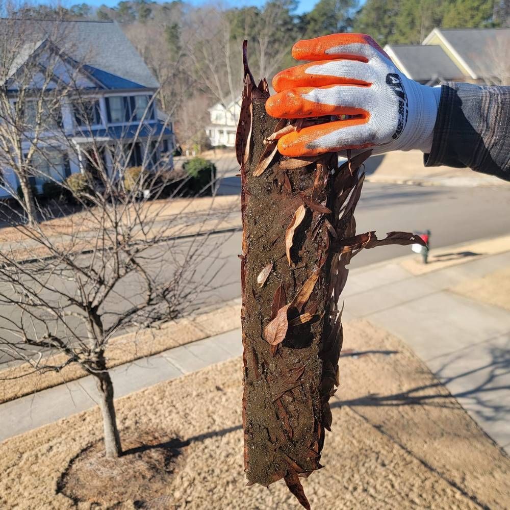 A person wearing orange gloves is holding a piece of wood.