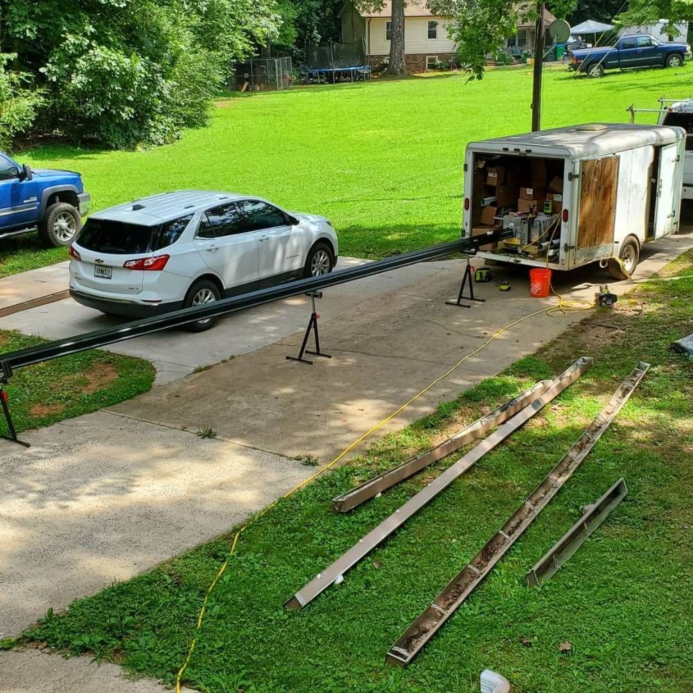 A car is parked in a driveway next to a trailer.